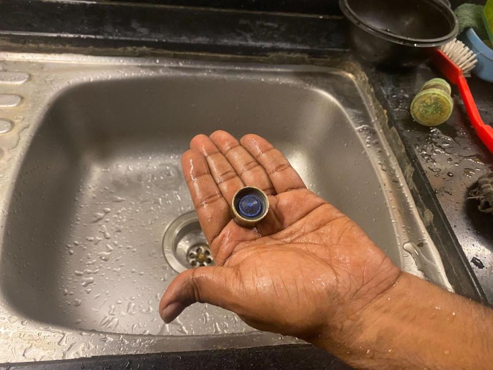 A resident shows a device for reducing the flow of water from a tap. Such devices have been installed in many apartments to regulate water supply amid the shortage (Stuti Mishra/The Independent)