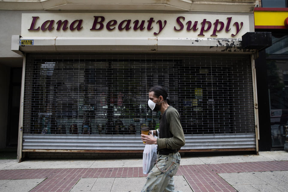 A shopper in a mask walks in front of a shuttered store in downtown Allentown, Pa., Friday, May 29, 2020. Unfilled potholes, uncollected trash, un-mowed grass and, most significantly, fewer cops on the street are some of what the city of Allentown, Pennsylvania, says it’s facing unless Washington helps it plug a multimillion-dollar budget hole left by the pandemic. (AP Photo/Matt Rourke)