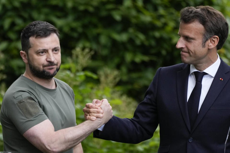 FILE - Ukraine President Volodymyr Zelenskyy, left, and France's President Emmanuel Macron shake hands at the end of a press conference at the Mariyinsky Palace in Kyiv, Ukraine, on June 16, 2022. The question of if and how Russia competes at the Olympics hangs over the 2024 Paris Summer Games. One year after the invasion of Ukraine began, Russia's reintegration into the world of sports threatens to create the biggest rift in the Olympic movement since the Cold War. (AP Photo/Natacha Pisarenko, File)
