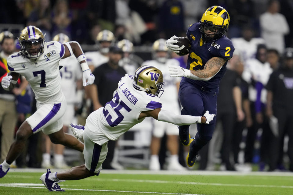 Michigan running back Blake Corum is tackled by Washington cornerback Elijah Jackson during the second half of the national championship NCAA College Football Playoff game Monday, Jan. 8, 2024, in Houston. (AP Photo/Godofredo A. Vasquez)