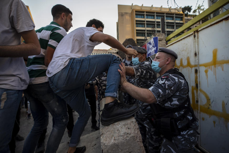 Anti-government protesters scuffle with Lebanese policemen after they removed a part of a concrete wall that was installed by security forces to prevent them from reaching the government palace in Beirut, Lebanon, Thursday, July 2, 2020. Major retailers in Lebanon announced Thursday they will temporarily close in the face of an increasingly volatile currency market and their inability to set prices while the local currency tumbles before the dollar. (AP Photo/Hassan Ammar)