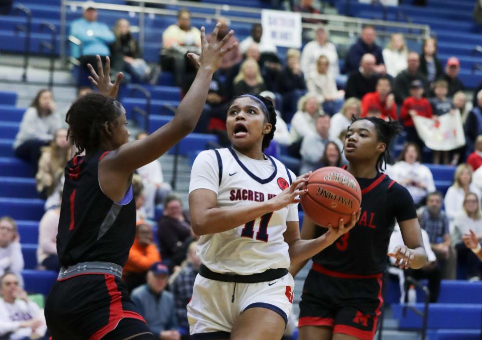 Sacred Heart’s ZaKiyah Johnson (11) split the Manual defense on her way to scoring during the Girls LIT Championship at the Valley High School gym in Louisville, Ky. on Jan. 28, 2023.  