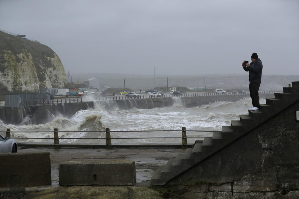 A man records the conditions as Storm Ciara hits Newhaven, on the south coast of England, Sunday, Feb. 9, 2020. Trains, flights and ferries have been cancelled and weather warnings issued across the United Kingdom and in northern Europe as the storm with winds expected to reach hurricane levels batters the region. (AP Photo/Matt Dunham)