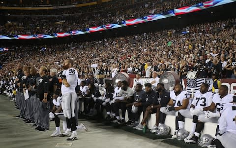 Oakland Raiders players sit on the bench during the national anthem  - Credit: USA Today