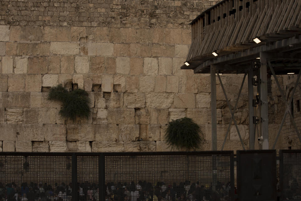 Worshippers pray in the women's section of the Western Wall, the holiest site where Jews can pray, in the shadow of the Mughrabi Bridge, a wooden pedestrian bridge connecting the wall to the Al Aqsa Mosque compound, in Jerusalem's Old City, Tuesday, July 20, 2021. The rickety bridge allowing access to Jerusalem's most sensitive holy site is at risk of collapse, according to experts. But the flashpoint shrine's delicate position at ground-zero of the Israeli-Palestinian conflict has prevented its repair for more than a decade. (AP Photo/Maya Alleruzzo)