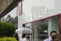 Workers chat under an umbrella outside the Tesla showroom in Beijing, Tuesday, May 30, 2023. China’s foreign minister met Tesla Ltd. CEO Elon Musk on Tuesday and said strained U.S.-Chinese relations require “mutual respect,” while delivering a message of reassurance that foreign companies are welcome. (AP Photo/Ng Han Guan)