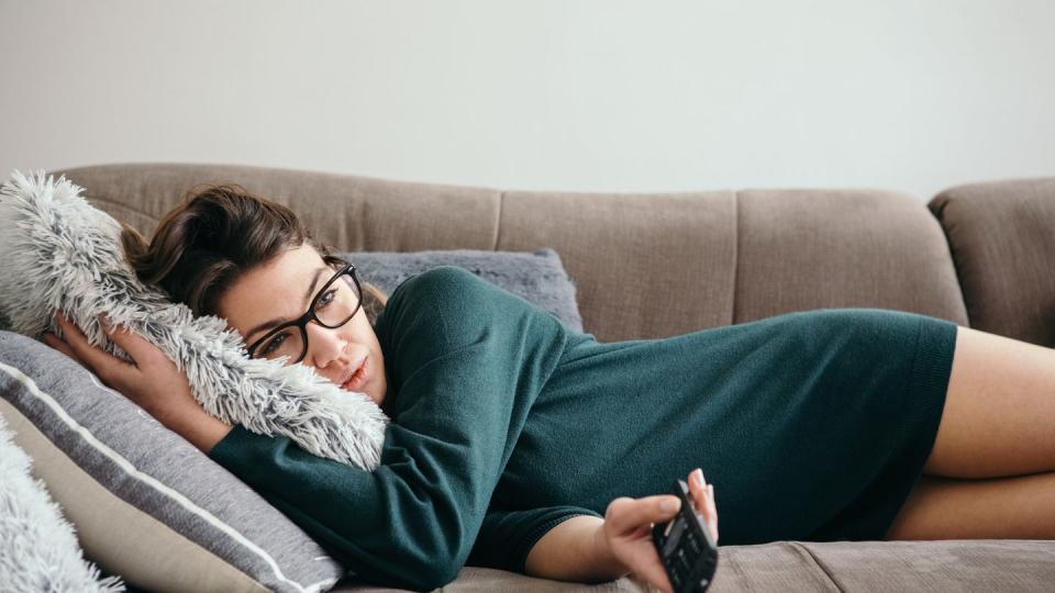 depressed woman changing channels on a tv remote