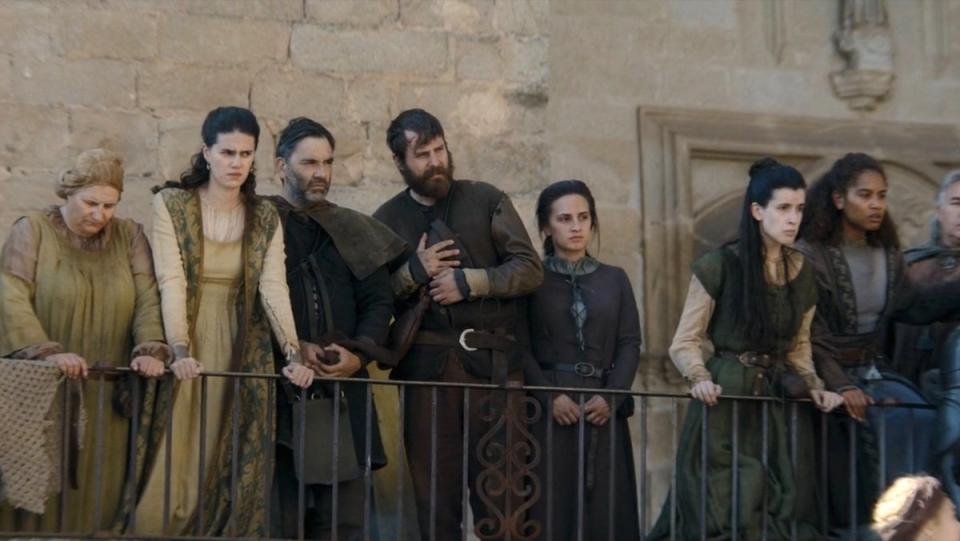 Upset smallfolk on a balcony look down on the streets of King's Landing on House of the Dragon