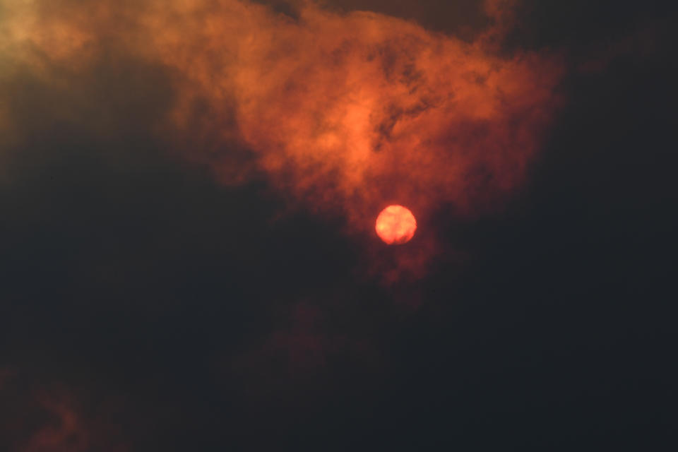 The sun shines through a thick cloud of smoke. The sky has turned red. 