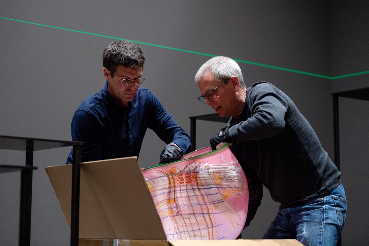 Chris Pfeifle, design builder, left, and Paul Arnhold, installer and lead packer, both with Chihuly Studio, pull a piece out of a box as they put together the Chihuly exhibition at the Biltmore Estate, March 20, 2024.