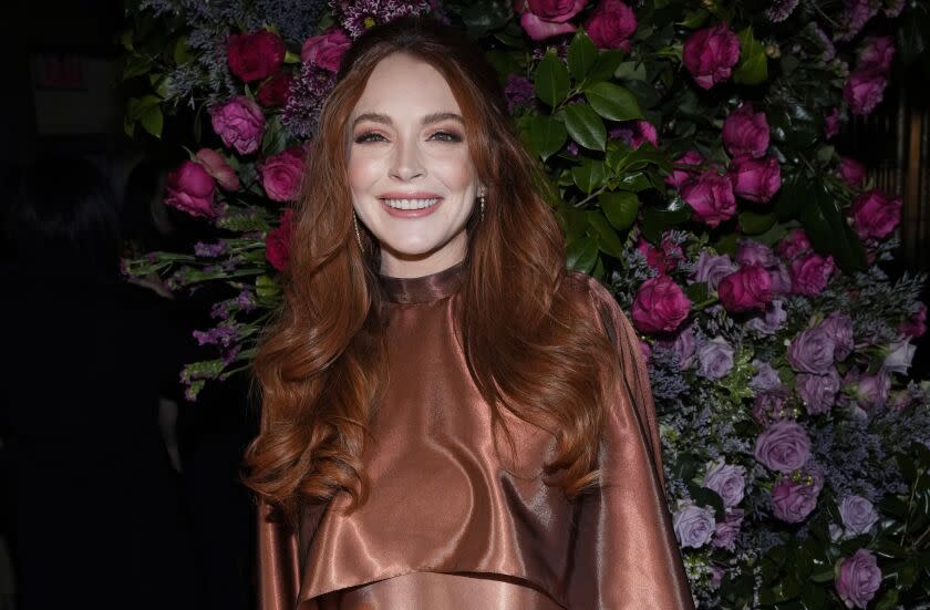 Lindsay Lohan in a copper dress against a floral backdrop