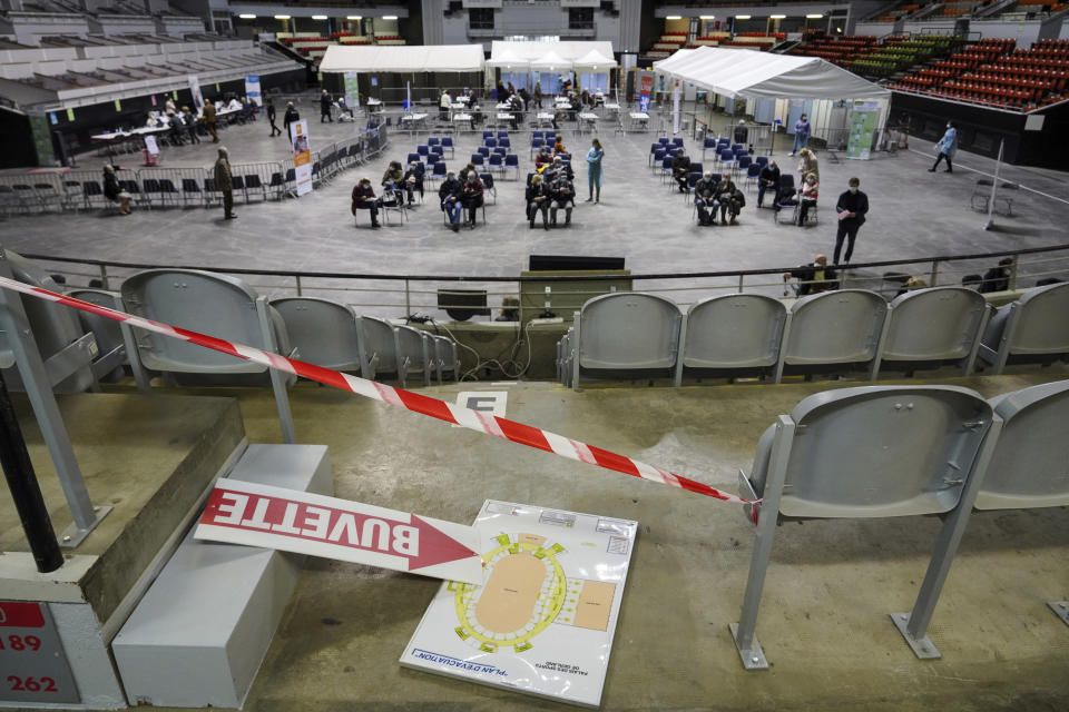 People wait after receiving the Pfizer/BioNTech vaccine against the COVID-19 in a vaccination center in the Lyon sports arena, central France, Thursday, Fev. 18, 2021. French Health Minister Olivier Veran promised stepped-up testing and vaccinations, but the government has resisted calls from some local doctors and leaders for a new lockdown. (AP Photo/Laurent Cipriani)