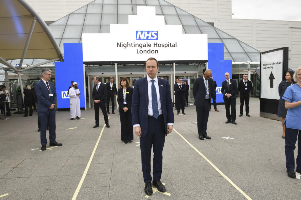 Britain's Health Secretary Matt Hancock and NHS staff stand on marks on the ground, put in place to ensure social distancing guidelines are adhered to, ahead of the opening of the NHS Nightingale Hospital at the ExCel centre in London, Friday April 3, 2020. The ExCel centre which has been converted into a 4000 bed temporary hospital NHS Nightingale amid the growing coronavirus outbreak. (Stefan Rousseau/Pool Photo via AP)