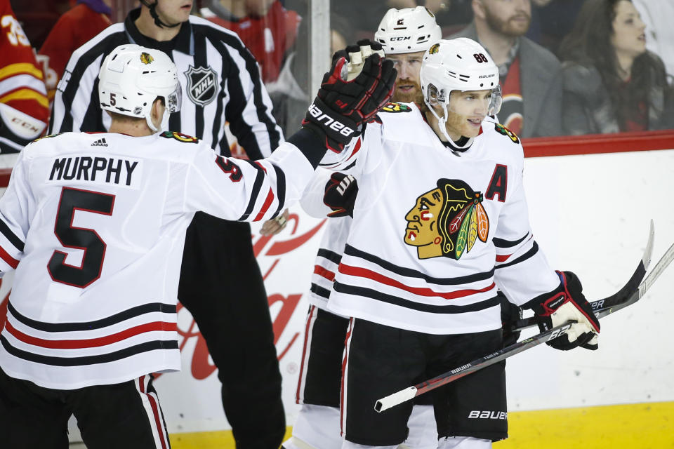 Chicago Blackhawks' Patrick Kane, right, celebrates his goal with teammates Duncan Keith, center, and Connor Murphy during the first period of an NHL hockey game against the Calgary Flames on Tuesday, Dec. 31, 2019, in Calgary, Alberta. (Jeff McIntosh/The Canadian Press via AP)