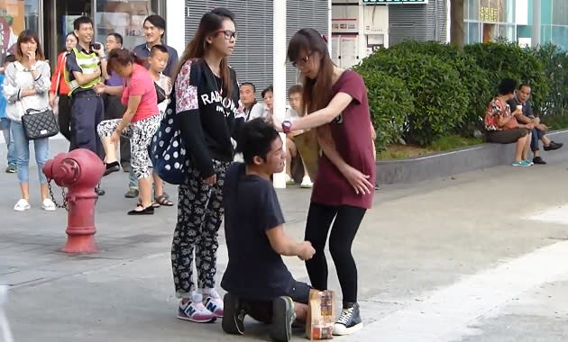 A Hong Kong woman slaps and scolds her boyfriend on a street. (Yahoo screengrab of YouTube video)