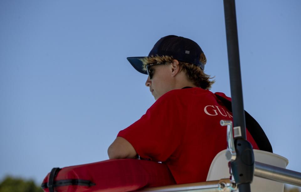 A young man sits in a lifeguard station.