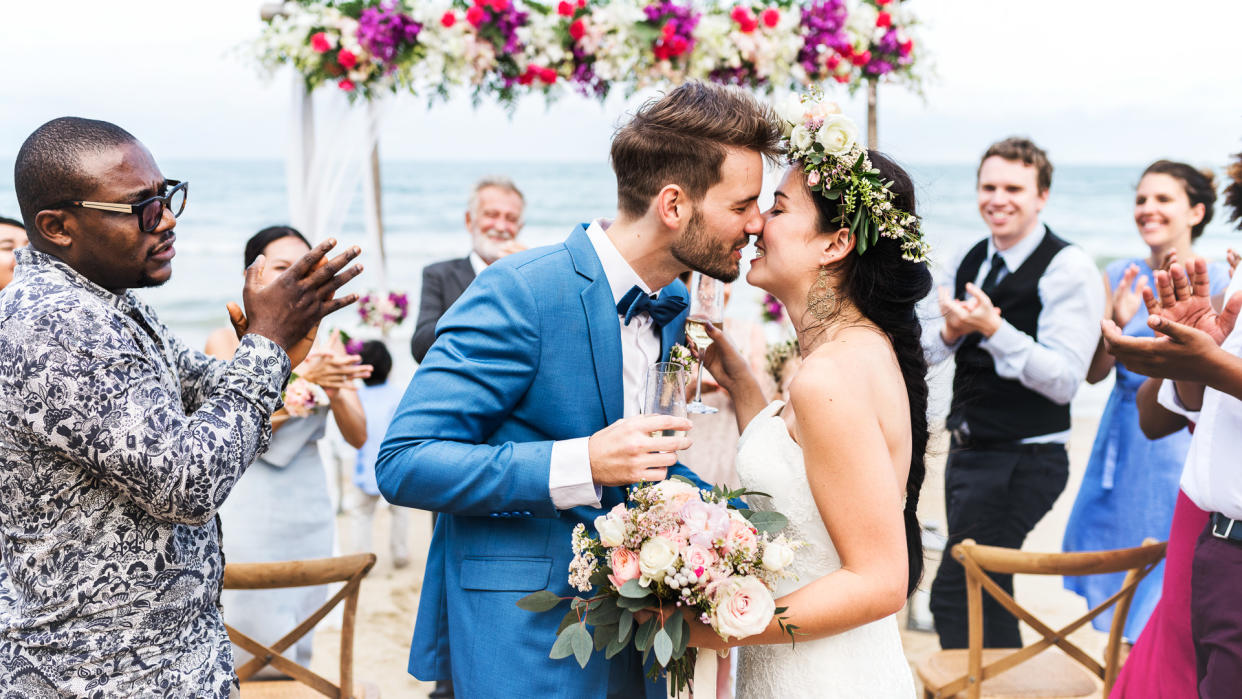 Young couple kissing at wedding reception.