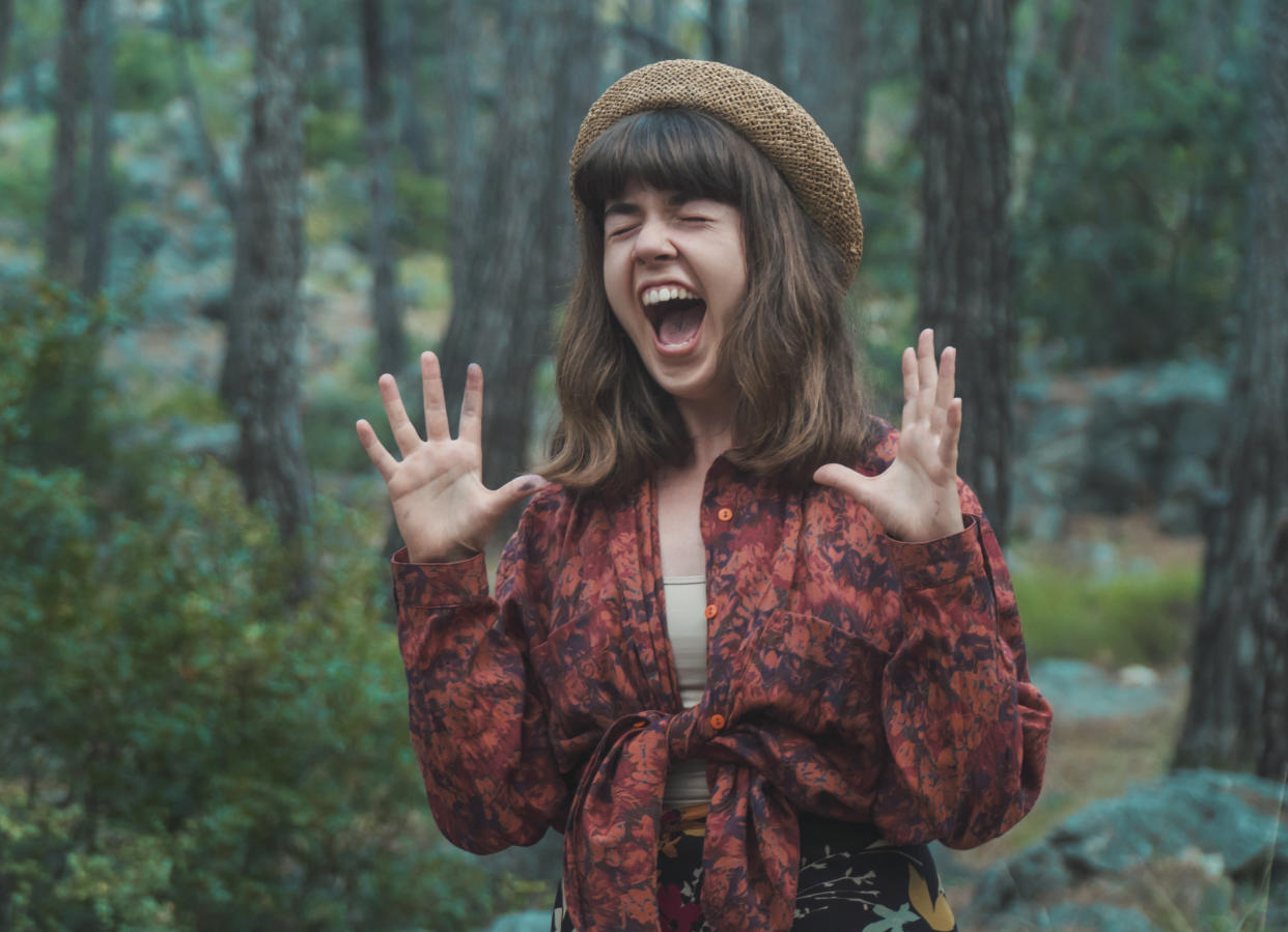 Portrait of screaming young woman against woodland area