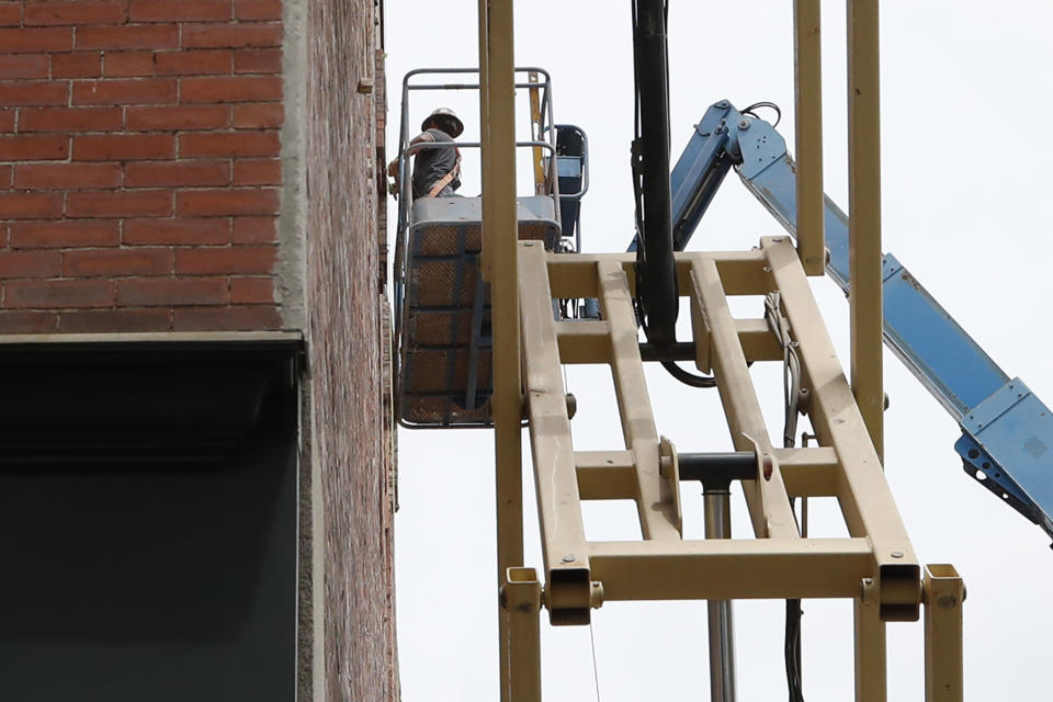 A man on a crane works to fix a building facade, Friday, June 5, 2020, in Lawrence, Mass. The U.S. unemployment rate fell unexpectedly in May to 13.3% — still on par with what the nation witnessed during the Great Depression — as states loosened their coronavirus lockdowns and businesses began recalling workers. (AP Photo/Elise Amendola)