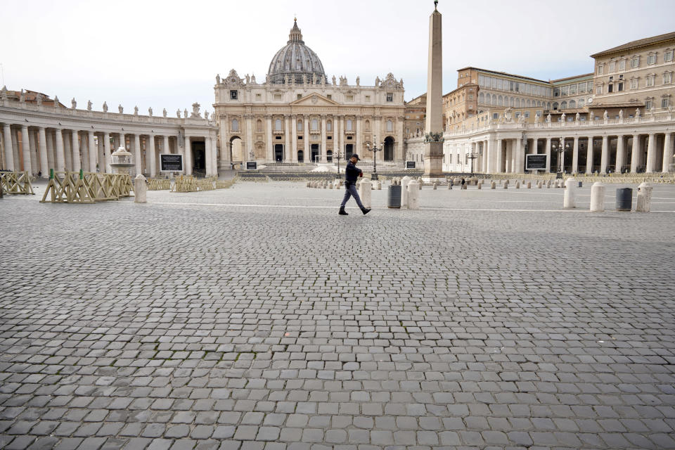 An Italian police officer walks in an empty St. Peter's Square after the Vatican erected a new barricade at the edge of the square, in Rome, Tuesday, March 10, 2020. Italy entered its first day under a nationwide lockdown after a government decree extended restrictions on movement from the hard-hit north to the rest of the country to prevent the spreading of coronavirus. (AP Photo/Andrew Medichini)