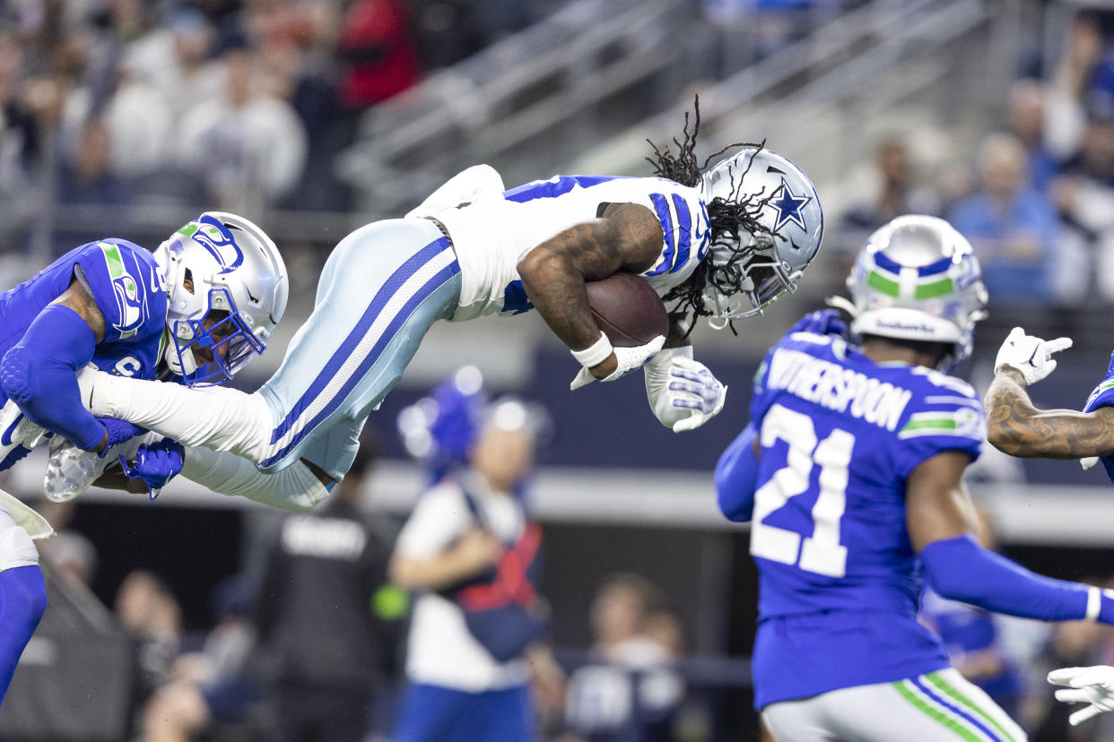 ARLINGTON, TEXAS - NOVEMBER 30: CeeDee Lamb #88 of the Dallas Cowboys dives as he's tackled by Quandre Diggs #6 of the Seattle Seahawks during an NFL football game between the Dallas Cowboys and the Seattle Seahawks at AT&T Stadium on November 30, 2023 in Arlington, Texas. (Photo by Michael Owens/Getty Images)