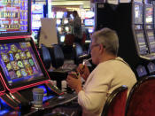 A gambler lights a cigarette at a slot machine in Harrah's casino in Atlantic City N.J., on Sept. 29, 2023. On Monday, April 29, 2024, Atlantic City's main casino workers union asked a judge to let it intervene in that lawsuit. (AP Photo/Wayne