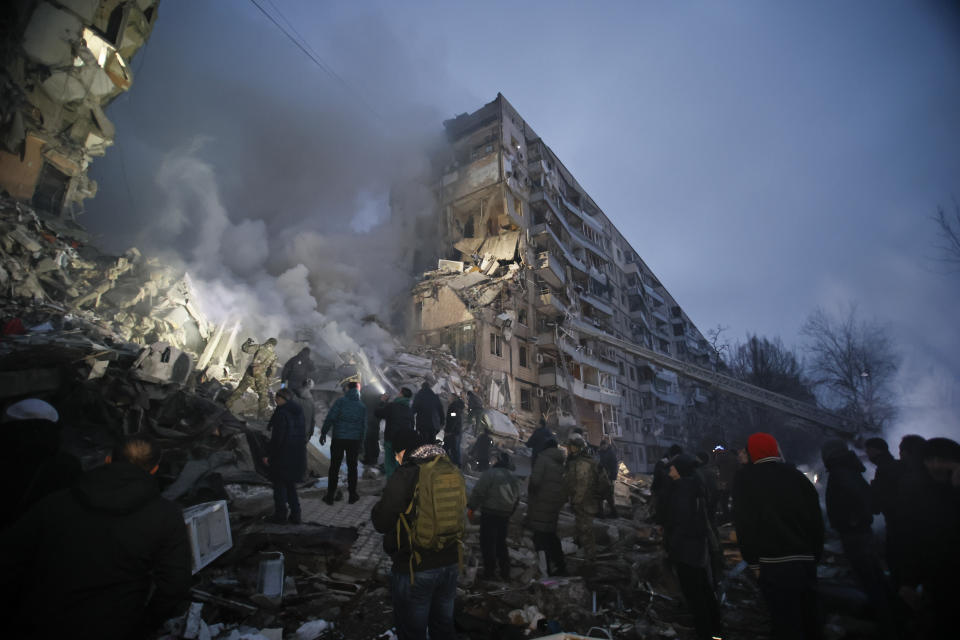 Emergency workers clear the rubble after a Russian rocket hit a multistory building leaving many people under debris in Dnipro, Ukraine, Saturday, Jan. 14, 2023. (AP Photo/Roman Chop)