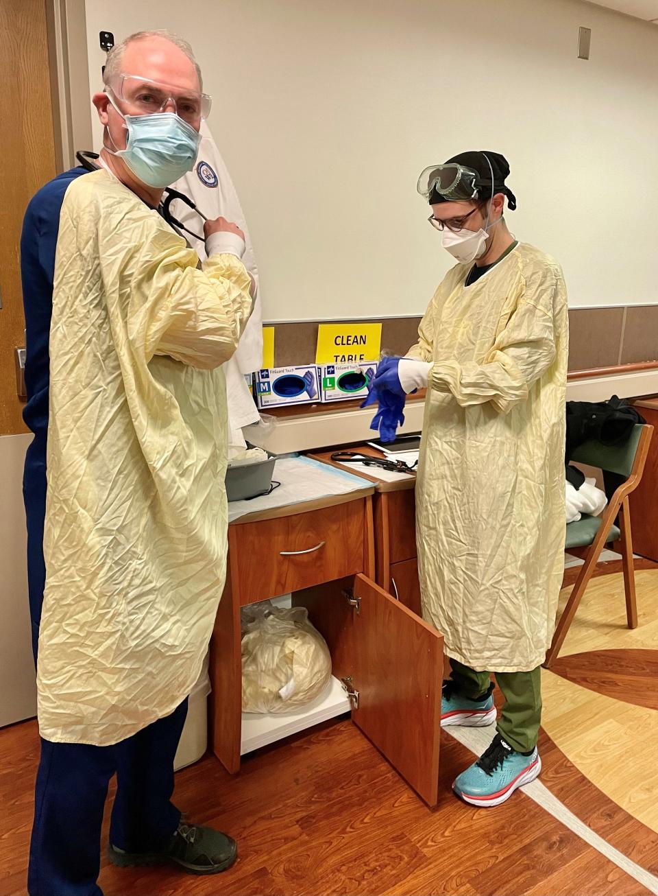 Dr. Paul Bozyk, left, and Dr. Matthew Weatherhead don gowns and other personal protective equipment before entering a patient's room at Beaumont Hospital in Royal Oak on Friday, Dec. 3, 2021. Bozyk is section head for pulmonary and critical care medicine the Royal Oak hospital and vice chair of the board of the Michigan State Medical Society.