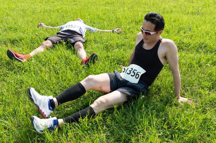 Two runners resting in the grass.