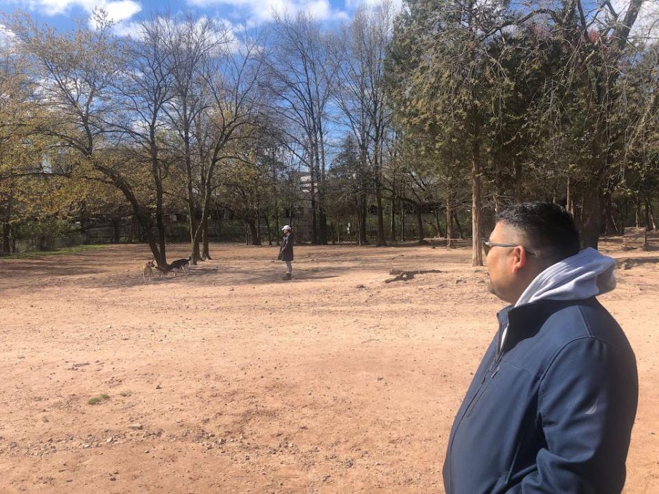 Juan Ramirez, at a dog park in Herndon, Virginia, said he hopes new housing will bring more affordability and young people to the suburban area where he grew up. In the background are vacant offices slated to be torn down to build apartments and townhouses