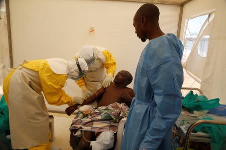 Medical stuff and an Ebola survivor treat Ebola patient Ibrahim Mupalalo inside the Biosecure Emergency Care Unit (CUBE) at the ALIMA (The Alliance for International Medical Action) Ebola treatment centre in Beni, in the Democratic Republic of Congo, March 31, 2019. Picture taken March 31, 2019. REUTERS/Baz Ratner