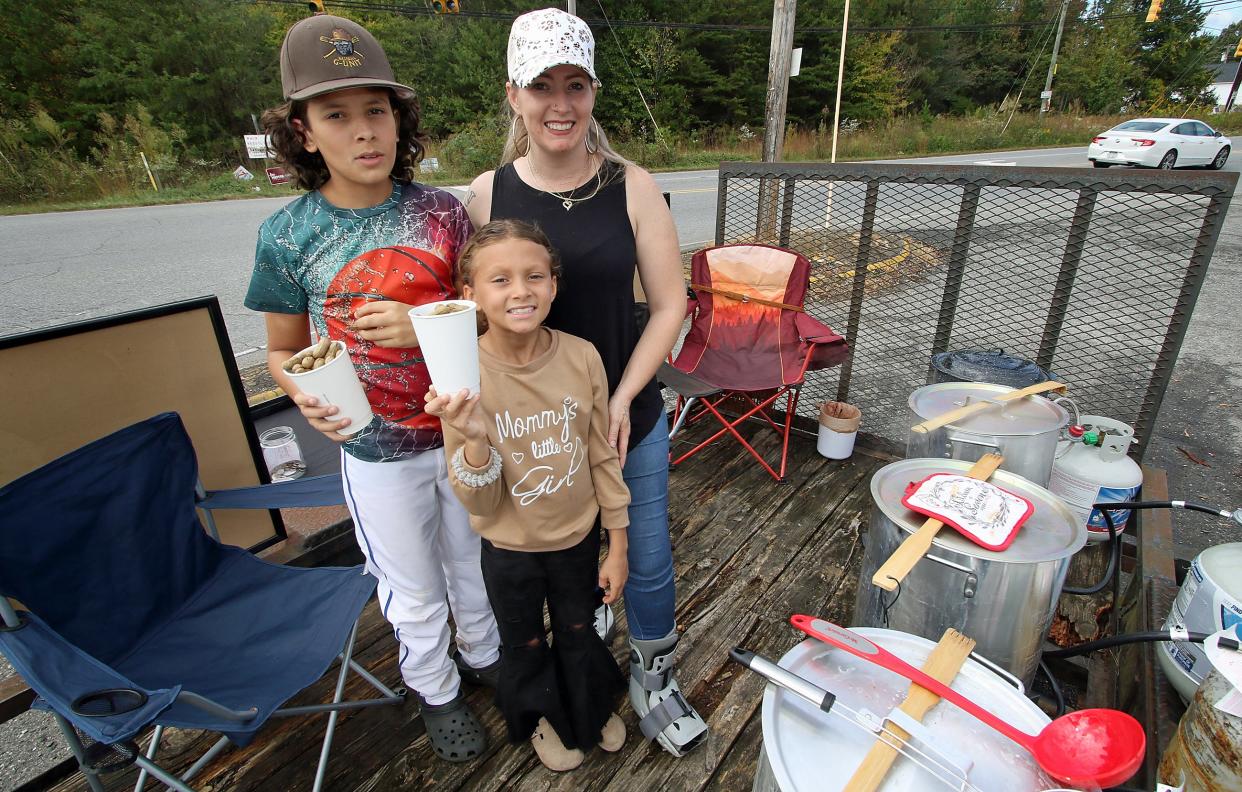 Kimberly “Mama Kim” Usery-Pettis, with her children, Zariah Pettis and Cason Usery-Pettis, work their boiled peanut stand Thursday afternoon, Oct. 12, 2023, at the corner of Hickory Grove Road and Woodlawn Street.