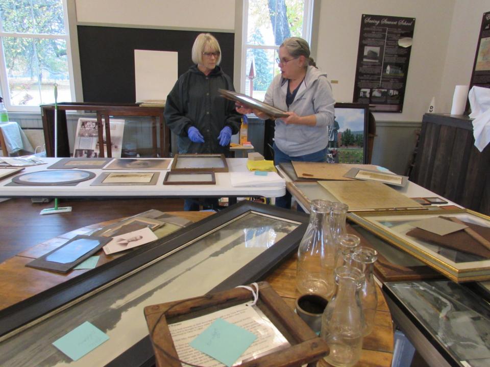 Beth Daugherty, left, and Claire Logue go through the photos salvaged from the Heritage House. Members of the Stow Historical Society have been removing the photos from their frames to allow them to dry and to wipe any soot off of them with a dry sponge.