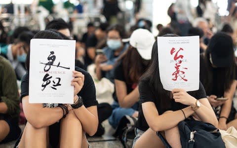 Protesters hold papers of conscience, left, and justice - Credit: &nbsp;PHILIP FONG/AFP