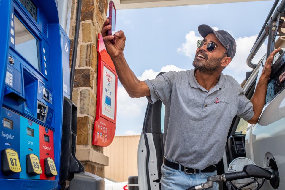 Man takes photo of prices at a gas station.