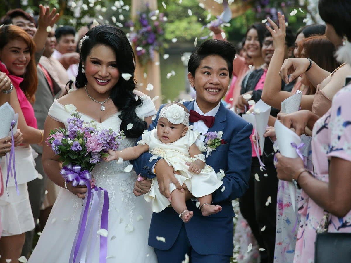 Bride Amornrat Ruamsin (L), 27, who is a transgender, holds up her five-month-old daughter with her groom Pitchaya Kachainrum (R), 16, during their wedding ceremony organised by a local TV show, in Bangkok, Thailand, February 9, 2018. The ceremony is not legally-binding as Pitchaya in under 17, the legal age for marriage in Thailand. The couple plan to officially wed after her birthday. 