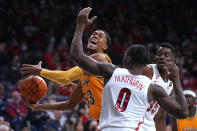 Wyoming guard Xavier DuSell (53) drives between Arizona guard Bennedict Mathurin (0) and center Christian Koloko during the first half of an NCAA college basketball game Wednesday, Dec. 8, 2021, in Tucson, Ariz. (AP Photo/Rick Scuteri)