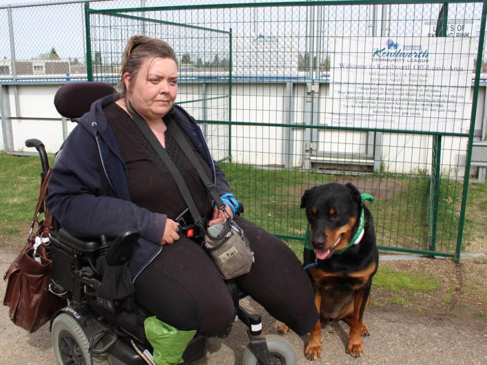 Marla Smith and Kuno outside the Kenilworth Community League's off-leash dog park. The park is meant to be accessible, but she can't entire it, or several others, with her wheelchair.  (Gabriela Panza-Beltrandi/CBC News - image credit)