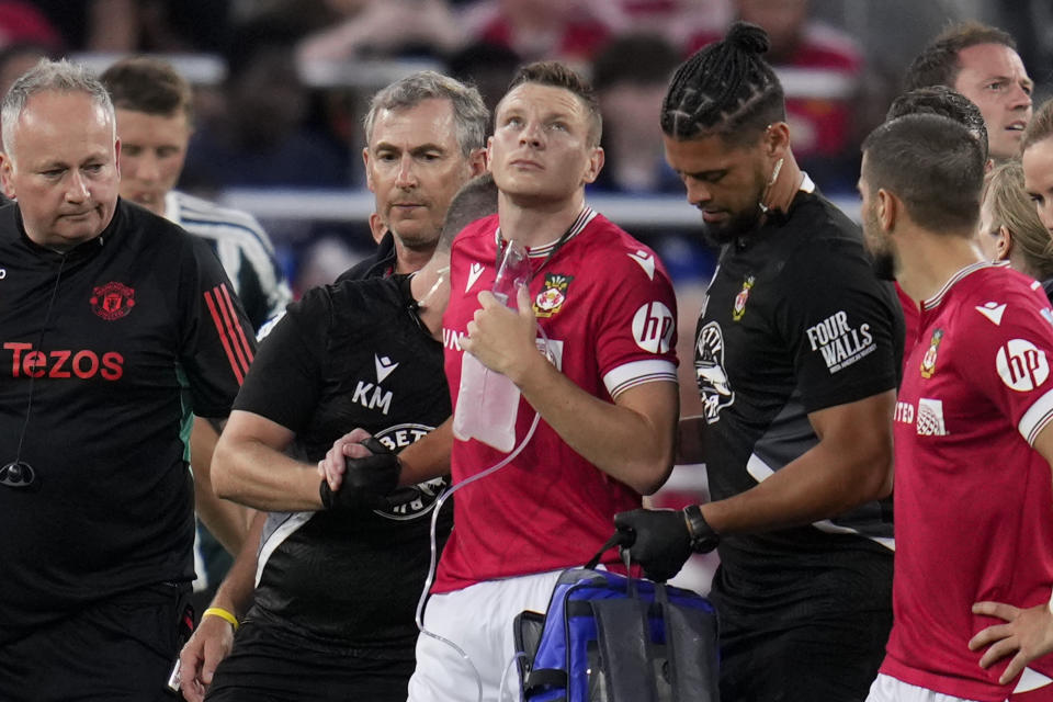 Wrexham forward Paul Mullin, center, is helped off the field after an injury during the first half of a club friendly soccer match against Manchester United, Tuesday, July 25, 2023, in San Diego. (AP Photo/Gregory Bull)