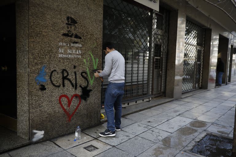 Un hombre intenta limpiar el acto de vandalismo con aguarrás en el frente de un edificio en Recoleta