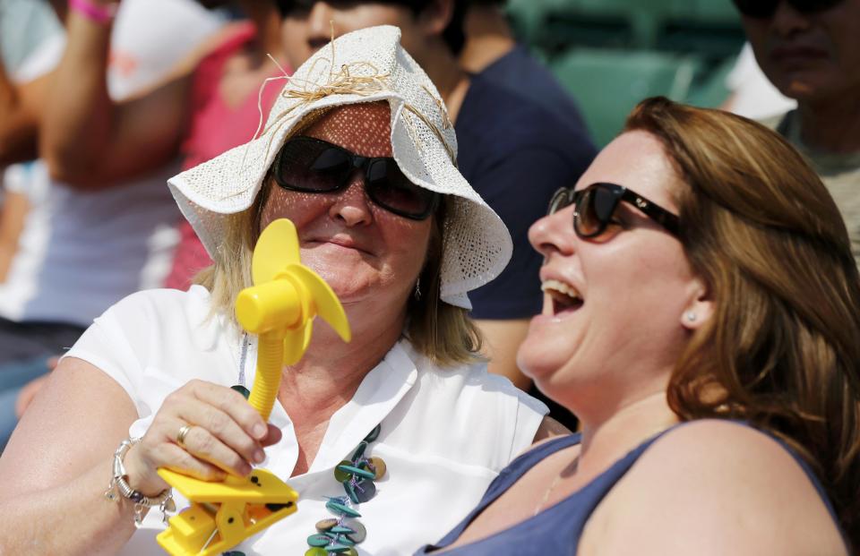 Spectators use mini electric fans to stay cool at the Wimbledon Tennis Championships in London, July 1, 2015. REUTERS/Suzanne Plunkett