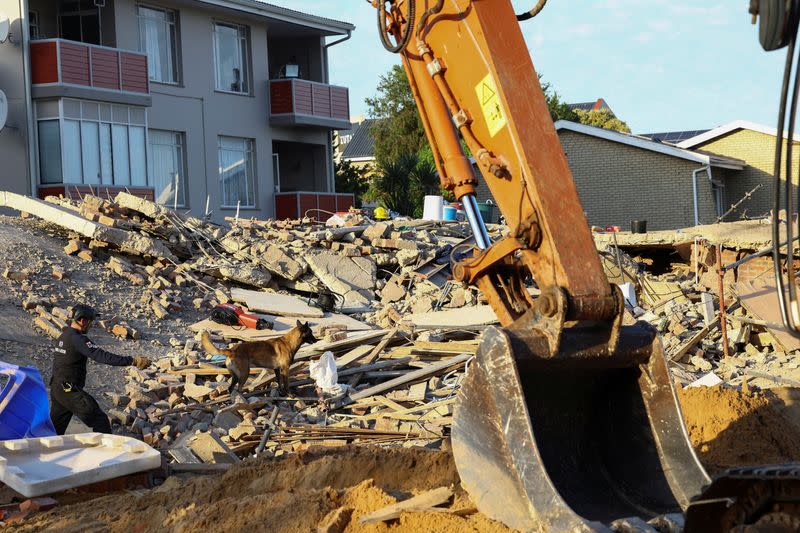 Rescuers work to rescue construction workers trapped under a building that collapsed in George