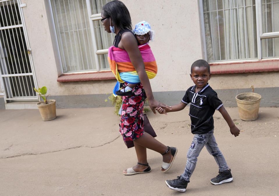 A mother walks home with her son after getting him vaccinated against measles at a clinic in Harare, Zimbabwe, Thursday, Sept. 15, 2022. Church members in Zimbabwe are getting their children vaccinated against measles in secret amid a deadly outbreak. It's to avoid being shunned by religious leaders who are opposed to modern medicine. (AP Photo/Tsvangirayi Mukwazhi)