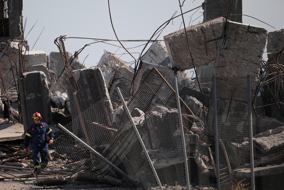 Pictured is a firefighter standing beside a demolished structure following an earthquake, at the port of Piraeus, Greece.