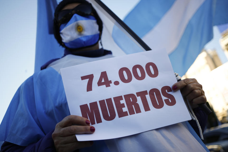 A man holds a sign that reads in Spanish "74.000 deaths" as he attends a protest against how the government of President Alberto Fernandez is handling the new coronavirus pandemic crisis, in Buenos Aires, Argentina, Tuesday, May 25, 2021. (AP Photo/Marcos Brindicci)