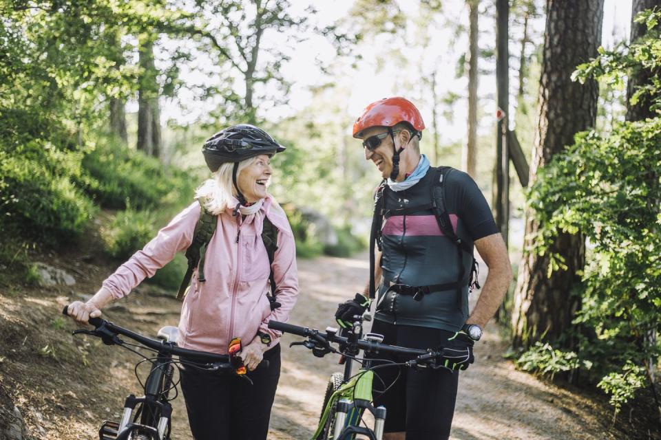 happy male and female friends talking to each other holding cycles