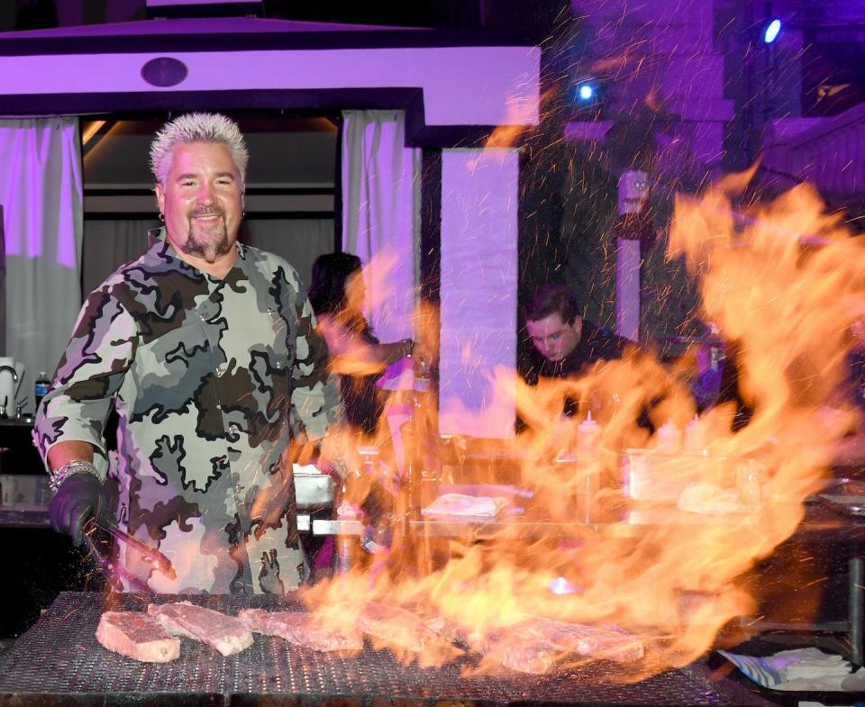 Chef Guy Fieri demonstrates how real men cook real meat in real fire. <a href="https://www.gettyimages.com/detail/news-photo/chef-and-television-personality-guy-fieri-prepares-food-at-news-photo/957632110?phrase=guy%20fieri%20food&adppopup=true" rel="nofollow noopener" target="_blank" data-ylk="slk:Ethan Miller/Getty Images;elm:context_link;itc:0;sec:content-canvas" class="link ">Ethan Miller/Getty Images</a>