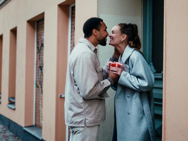 A young couple kissing at the doorway with coffees