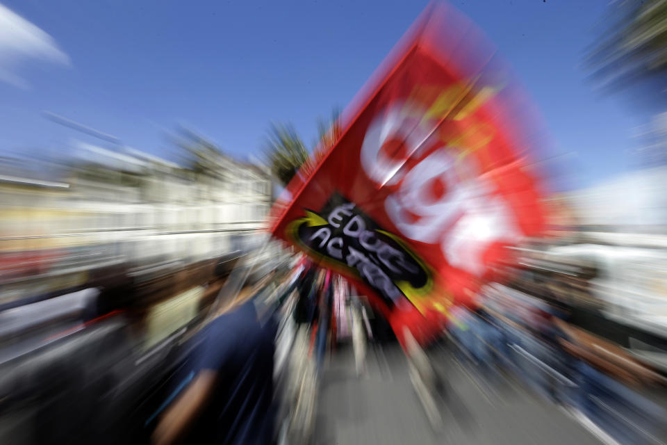 A public sector worker holds a CGT labor union flag during a demonstration in Marseille, southern France, Thursday, May 9, 2019. French unions are holding strikes and protests against 120,000 job cuts and other deep changes to France's huge public sector by President Emmanuel Macron's government. (AP Photo/Claude Paris)