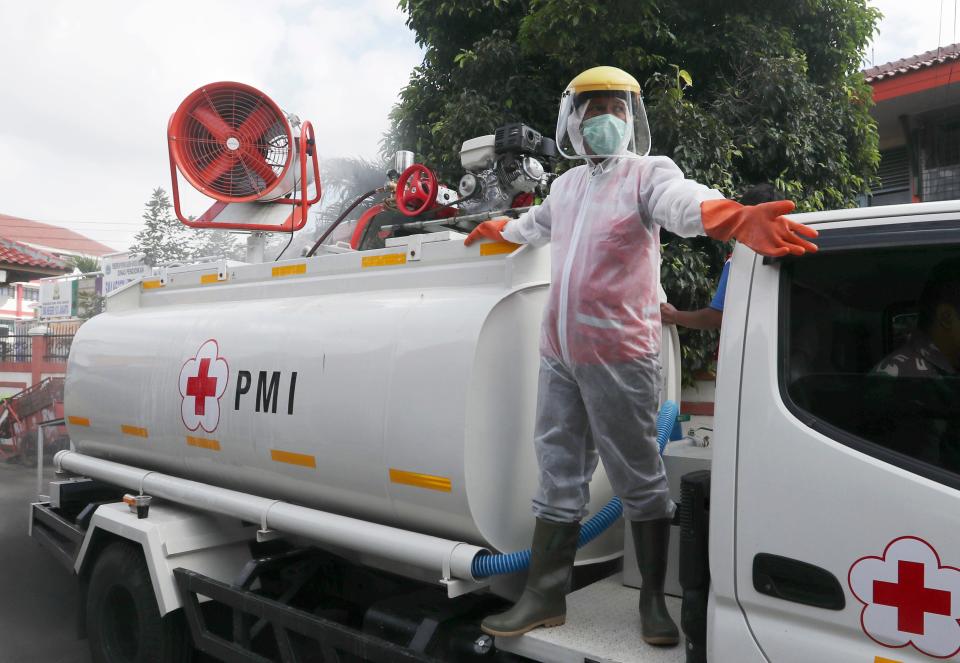 A member of Indonesian Red Cross stand on the back of a truck and spray disinfectant in an attempt to curb the spread of coronavirus outbreak at a neighbourhood in Jakarta, Indonesia, on April 8.